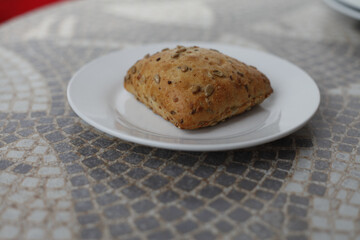 A fresh, seeded bread roll on a white plate, ready to be enjoyed.