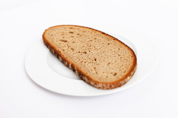 A slice of bread on a white plate against a white background.