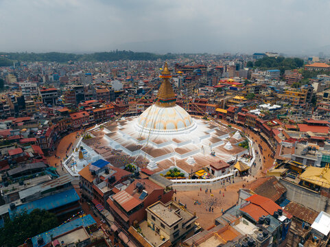 Aerial view of the Boudhanath Stupa, a gleaming white dome with a golden spire, standing majestically amidst the vibrant urban sprawl, Kathmandu, Bagmati Province, Nepal.