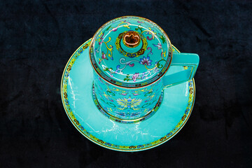 Close up view of turquoise china cup on the black background