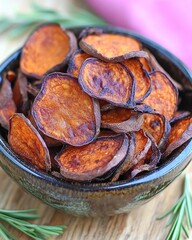 Bowl of golden sweet potato chips with rosemary garnish