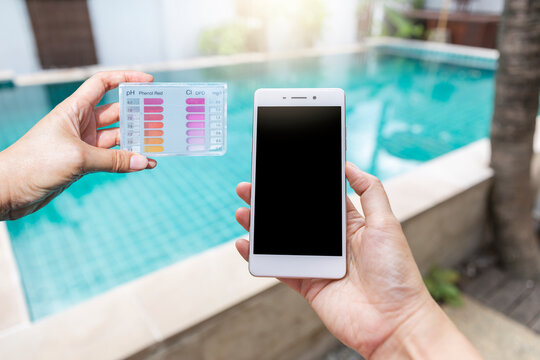 Smartphone and water tester in girl hand over swimming pool background, online quality control on smartphone