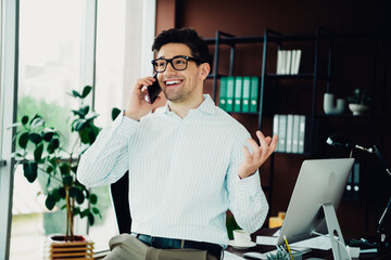 Confident young businessman enjoying a phone call in a modern office environment, reflecting success and professionalism