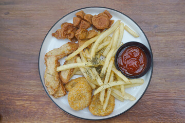 A delicious plate of golden fried snacks with ketchup and crispy fries on a wood background