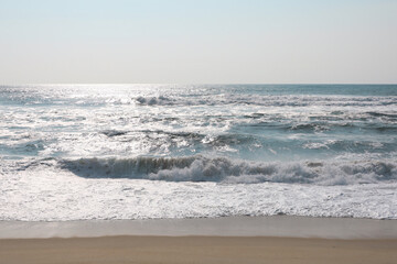 Ocean waves on the sandy coast of Portugal. Sunny clear day at sea