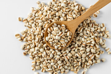White Sorghum Grains in a Wooden Spoon on a White Background
