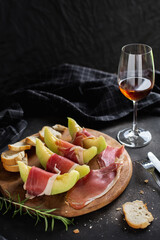 Fresh Melon with Prosciutto and Bread on Wooden Board with Wine