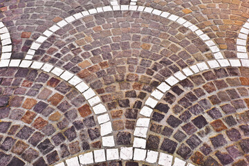 NEW ITALIAN PAVING MADE WITH PORPHYRY STONE BLOCKS AND WHITE MARBLE of cubic shape in a pedestrian zone placed in a shape known as a peacock tail