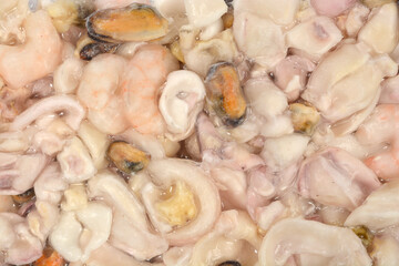 An extreme close-up macro shot shows the texture of mixed frozen seafood pressed tightly against the vacuum-sealed plastic packaging