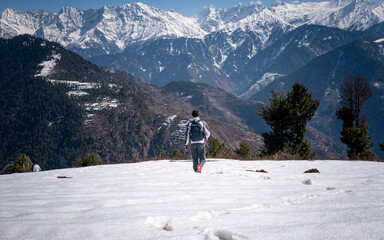 Hiker walking in snow with mountain landscape in background