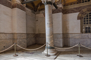Ancient marble column in historic building interior with rope barrier