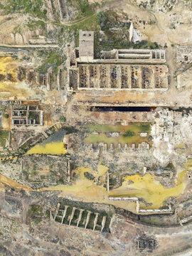 Aerial view of the oxidized earth and abandoned structures of the Riotinto Mines reveal a tapestry of rusty hues and decaying architecture, Minas de Riotinto, Andalusia, Spain.