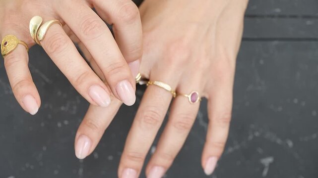 Hands adorned with unique rings display a lovely collection in a well-lit space. The soft nails complement the intricate jewelry, highlighting creativity and style.