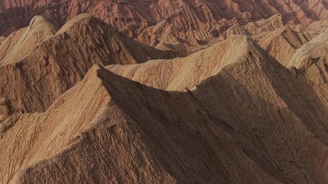 Aerial view of arid, rugged landscape featuring dramatic rock formations and textures carved by erosion in Hongshan Stone Forest, Kuqe, China.