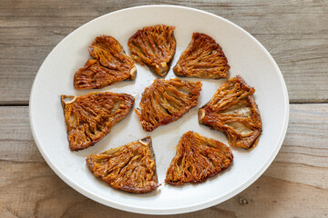 Pieces of fried parasol mushrooms (Macrolepiota procera) on a plate. Polish cuisine. Rustic wooden background.