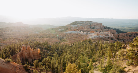Bryce Canyon at first light, panorama photo from Rim Trail at Sunrise Point over canyon, contre-jour shot into sun with lens flares and copy space