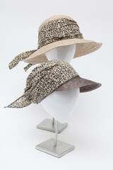 Two stylish hats with leopard print fabric on display against a white background.