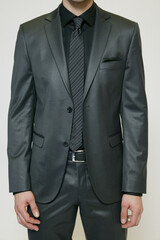 Man in a stylish gray suit with a black shirt and striped tie.