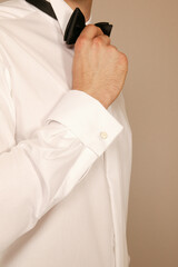 Man adjusting his bow tie and cufflink