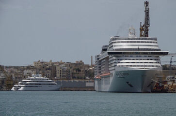 Modern cruise ship cruiseship liner being modernized over-hauled repaired refitted maintenanced by shipyard in Malta with dock and cranes