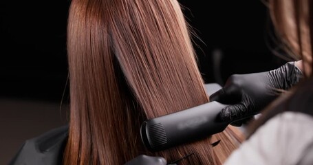 Sleek hair straightening process with professional flat iron technique in salon.