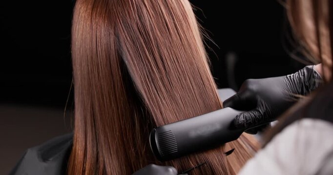 Sleek hair straightening process with professional flat iron technique in salon.