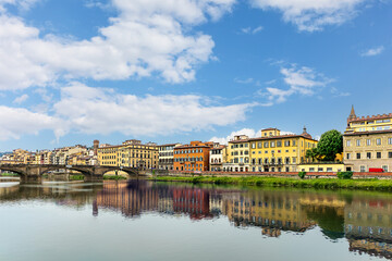 Naklejka premium View of the Arno River, charming buildings, and vibrant skies in Florence, Italy on a sunny day