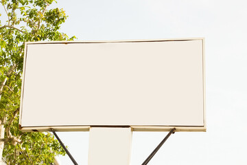 Metal,white and blank surface advertising sign on a  white sky with tree