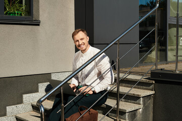 Young university teacher enjoying a moment outdoors on campus steps in bright sunlight