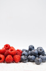 Raspberries and blueberries are a healthy colorful nutritious breakfast or dessert. A closeup shot that shows the juicy details. Perfect for a wallpaper or celebration card. 