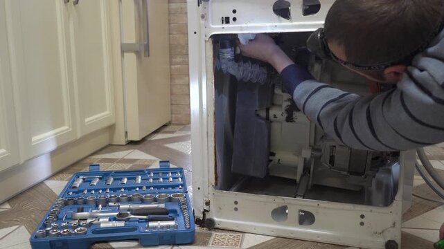 engineer repairs washing machine, man repairs washing machine with headlamp