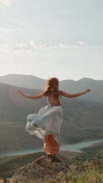Slow motion vertical video redhead woman standing arms wide mountain peak windy river valley cinematic lifestyle freedom inspiration beauty nature mindfulness