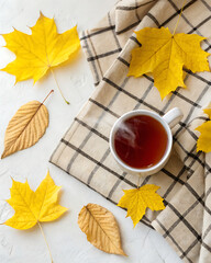Cozy composition in flat lay style, golden autumn. A cup of steaming tea, a soft blanket and scattered yellow leaves