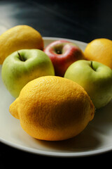Apples and lemons on white dish