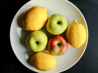 Apples and lemons on white dish