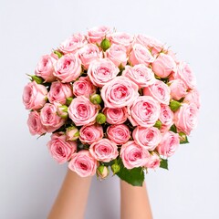 Hands presenting a lush bouquet of pink spray roses
