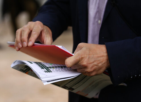 Carpeta, papeles y revista en manos de hombre trabajando con traje