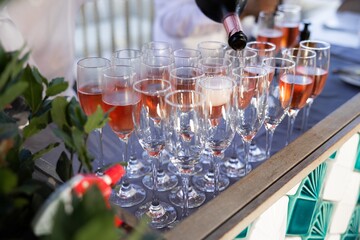 Pouring sparkling rosé into champagne flutes at event
