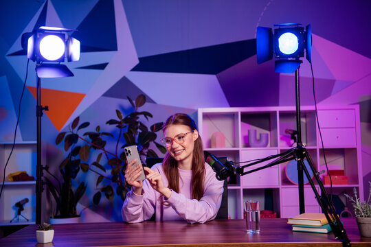 Charming professional girl recording a live blog with neon lights in a creative home office environment