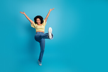 Obraz premium Excited young multiethnic woman posing playfully against a blue background showing a gesture of happiness and joy