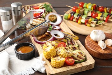 Vegetarian barbecue. Tasty grilled vegetables, spices and sauce on wooden table, closeup