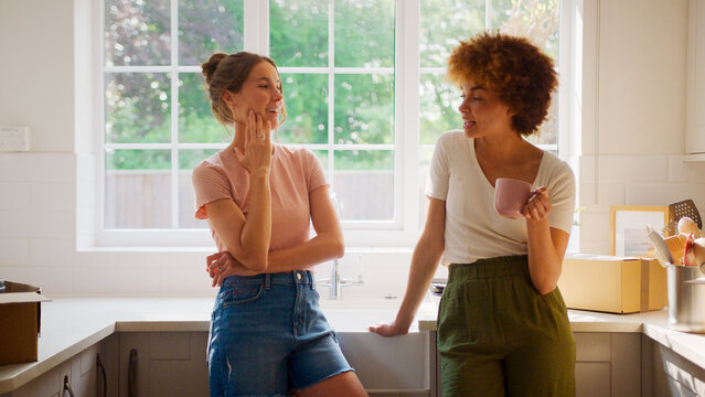 Two Female Friends Or Same Sex Couple Taking A Coffee Break From Unpacking On Moving Day In New Home