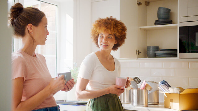 Two Female Friends Or Same Sex Couple Taking A Coffee Break From Unpacking On Moving Day In New Home - Powered by Adobe