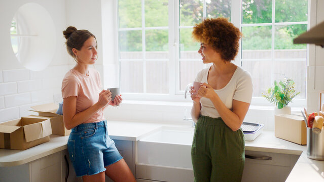 Two Female Friends Or Same Sex Couple Taking A Coffee Break From Unpacking On Moving Day In New Home