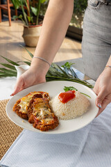 Woman serving chicken parmesan schnitzel with rice