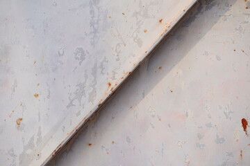 Abstract close-up of white painted metal surface with diagonal beam and rust spots