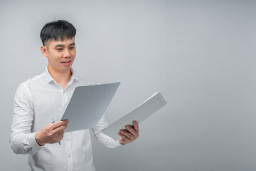 A handsome young Asian man looks pleasantly surprised while reviewing a document or financial statement. This concept is ideal for business, finance, investment, technology, and advertisement.


