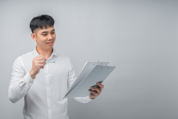 A handsome young Asian man looks pleasantly surprised while reviewing a document or financial statement. This concept is ideal for business, finance, investment, technology, and advertisement.

