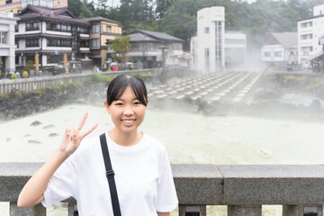 草津温泉旅行で湯畑に来ている10代の女性