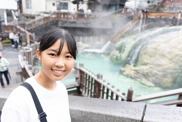 草津温泉旅行で湯畑に来ている10代の女性